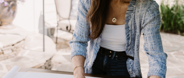 Founder Chelsea Secor is standing outside arranging fabric and wallpaper samples together for an interior design project